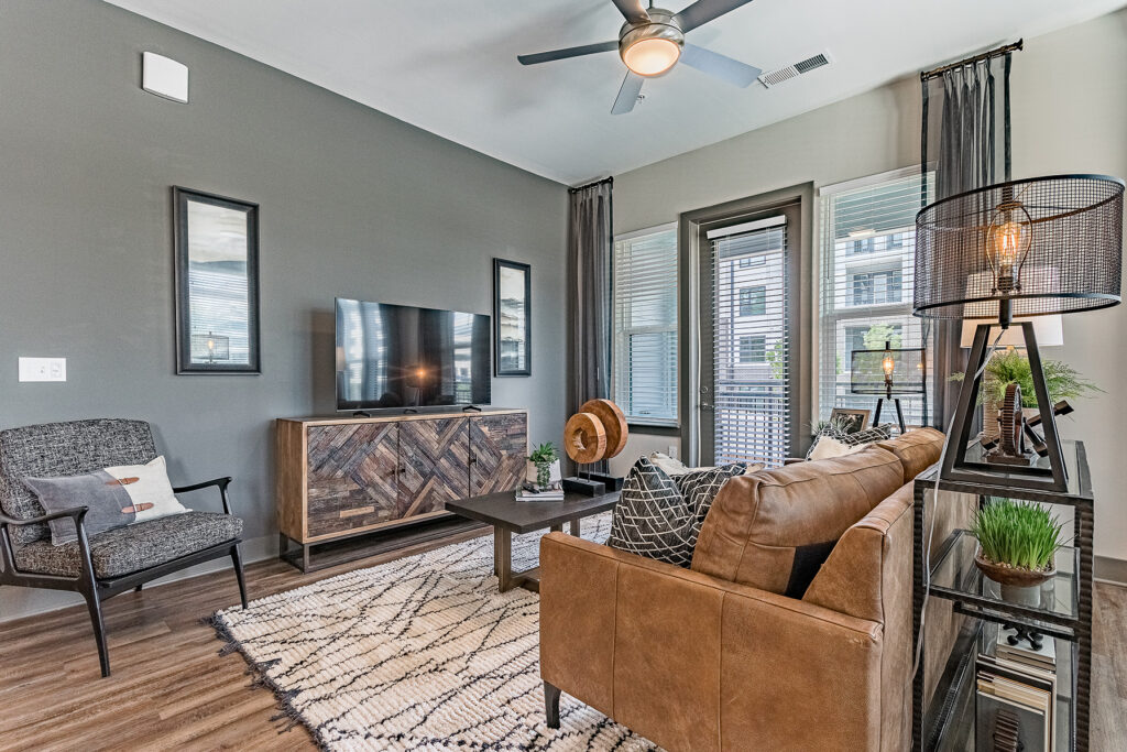 A modern living room with a gray color scheme, brown leather couch, and wooden TV stand.